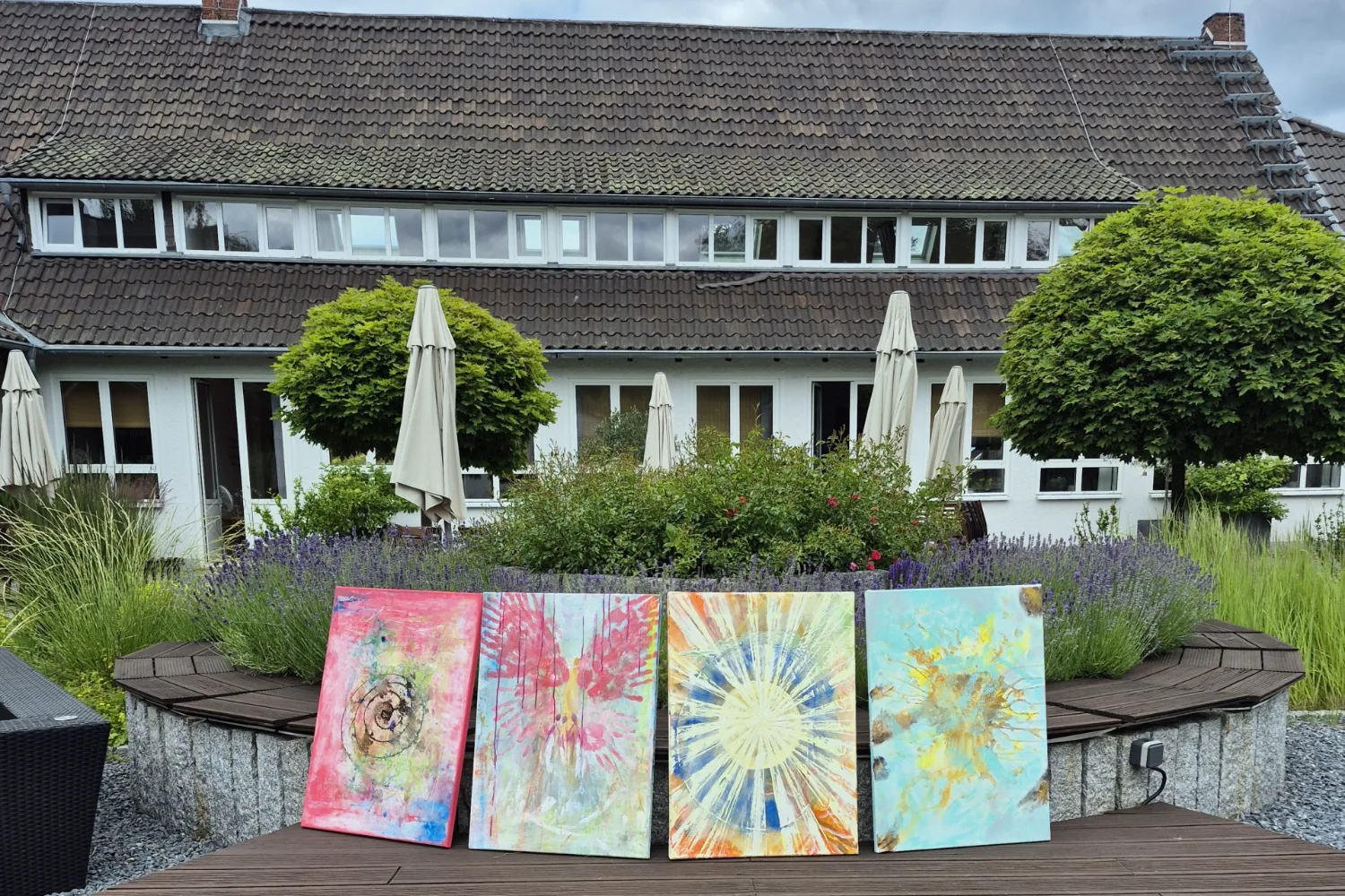 Vier fertige Seelenbilder stehen auf der Holzterrasse des Sampurna Seminarhauses